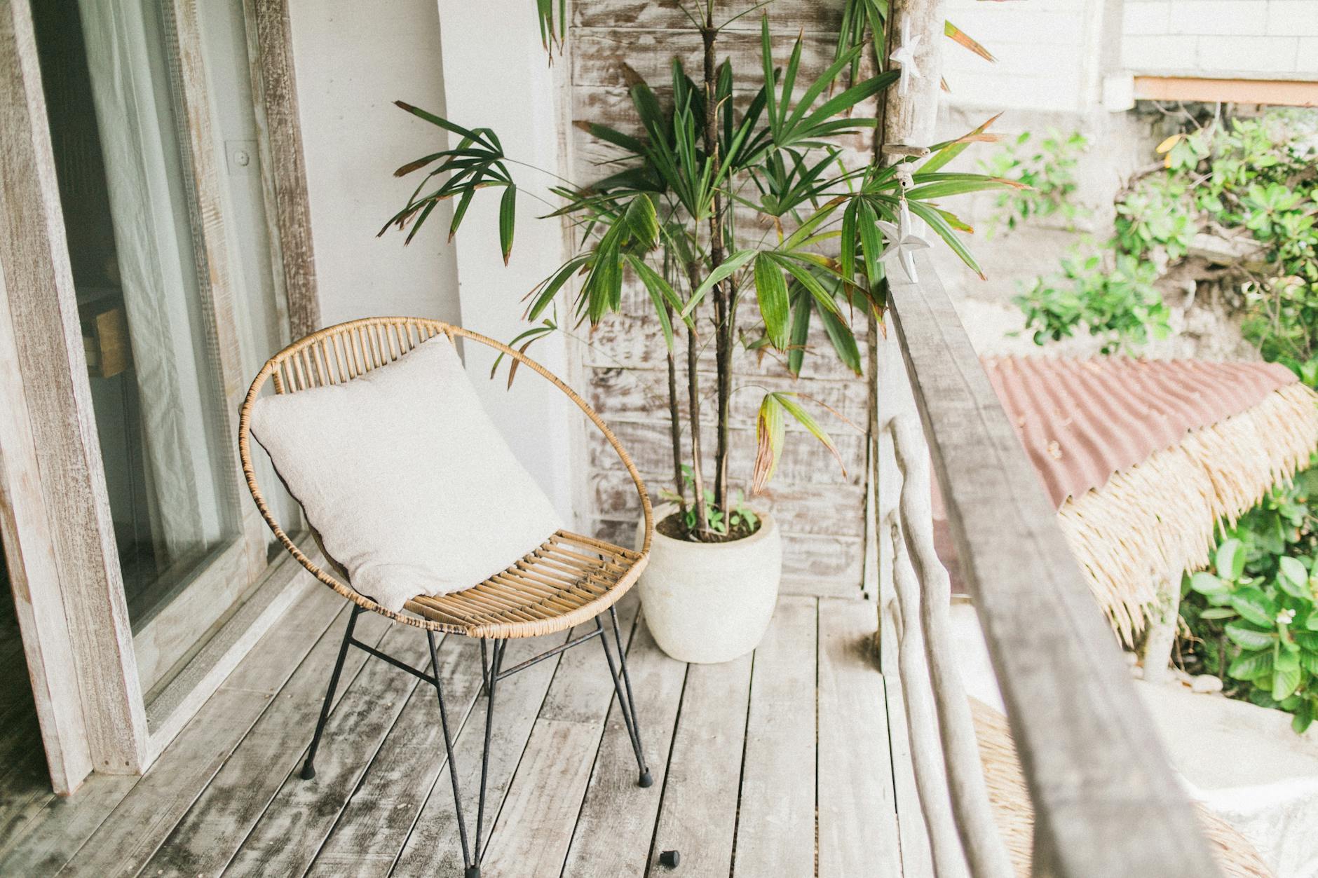 Jak udekorować balkon na lato, by był przytulny, funkcjonalny i pełen naturalnego uroku Przytulny balkon z białą poduszką i doniczkową rośliną przy drewnianym domu